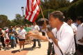 Primary view of [Man with a microphone addresses the crowd while pointing outward]