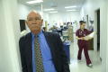 Primary view of [Eddy Herrera leans against doorway with clinic staff member in the background]