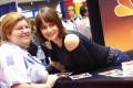 Photograph: [Gabriela leans over table to take photo with fan]