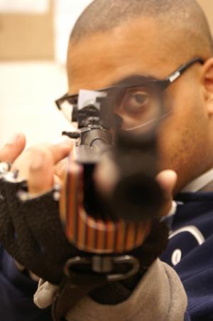 Primary view of object titled '[Student aiming his air rifle during practice]'.