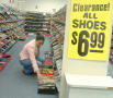 Primary view of [Woman kneeling next to shelves of shoes]