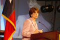 Photograph: [Woman in pink suit speaking at podium with Texas flag in background]