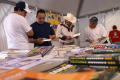 Primary view of [Men looking at books on tables under tent]