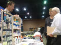 Primary view of [Man and woman talking to man with display of medical supplies]