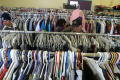 Primary view of [Three people look at the clothing at Dallas Catholic Charities]