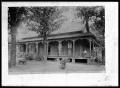 Photograph: [Unidentified House with Man on Porch]