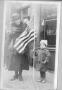 Photograph: Woman Standing Next to Her Young Child Who is Holding a Flag