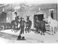 Photograph: Two Firemen with Four Horses in Front of Their Station
