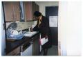 Photograph: [Woman at Sink in Kitchen]