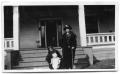 Photograph: Two women and a child in front of the steps to a house