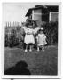 Photograph: Two children standing next to a fence in the backyard of a house