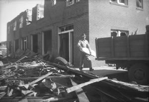 Primary view of object titled '[Photograph of Man Cleaning Debris After Tornado]'.