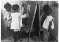 Photograph: [Four Black Children Painting on an Easel]