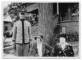 Photograph: [A man in uniform and two men standing near a tree]