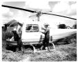Photograph: Cowboys Looking at a Bell Helicopter on the SMS Ranch