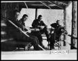 Photograph: Four Men Sitting on Porch with Guitar