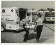 Photograph: [Two Men Carrying Stretcher to Ambulance]