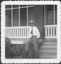 Primary view of [Mr. Albert George seated on the brick rail in front of the ranch house]