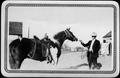 Primary view of [Man wearing a suit and hat, and holding the lead rope of a paint horse]