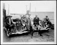 Photograph: [Group of men by two automobiles with deer bodies strapped to them]