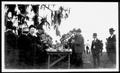 Primary view of [Group of men gathered around a table for a cook out at Camp George]