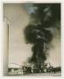 Photograph: [Cloud of Black Smoke Rising from Metal Building]