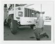 Photograph: [Man kneeling beside a City of Denton truck]