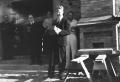 Photograph: [Robert Gribble Speaking Outside Shelton Chapel While Holding Brick]