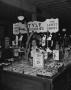 Photograph: [Woman Standing Behind a Counter in a Store]
