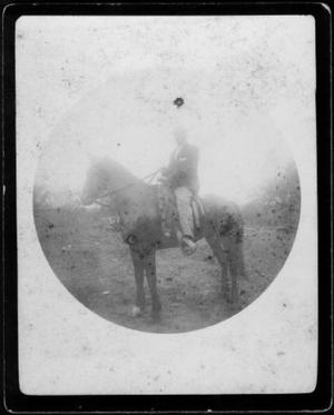 Primary view of object titled '[A man on horseback wearing light colored pants, dark jacket, white shirt, and a hat]'.