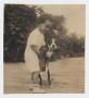 Photograph: [Photograph of Child Standing While Holding a Dog]
