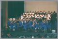 Photograph: [Band and choir ensemble playing on stage]