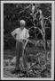 Photograph: [W. A. Hughes standing in his garden holding a garden tool]