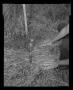Photograph: [Photograph of an individual uncovering a helicopter part in a field]