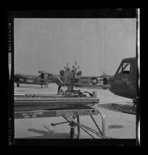 Primary view of object titled '[Photograph of a large piece of equipment and two YUH-1D Iroquois helicopters]'.