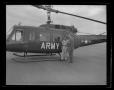 Photograph: [Photograph of two men standing outside a YUH-1B Iroquois helicopter]