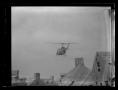 Thumbnail image of item number 1 in: '[Photograph of a UH-1B Iroquois helicopter as it flies over a war-zone simulation training area]'.