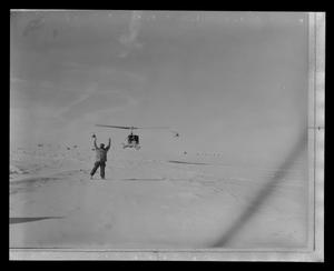 Primary view of object titled '[Photograph of a man flagging down three helicopters]'.