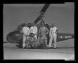 Photograph: [Six men in jumpsuits standing in front of a Marine helicopter]