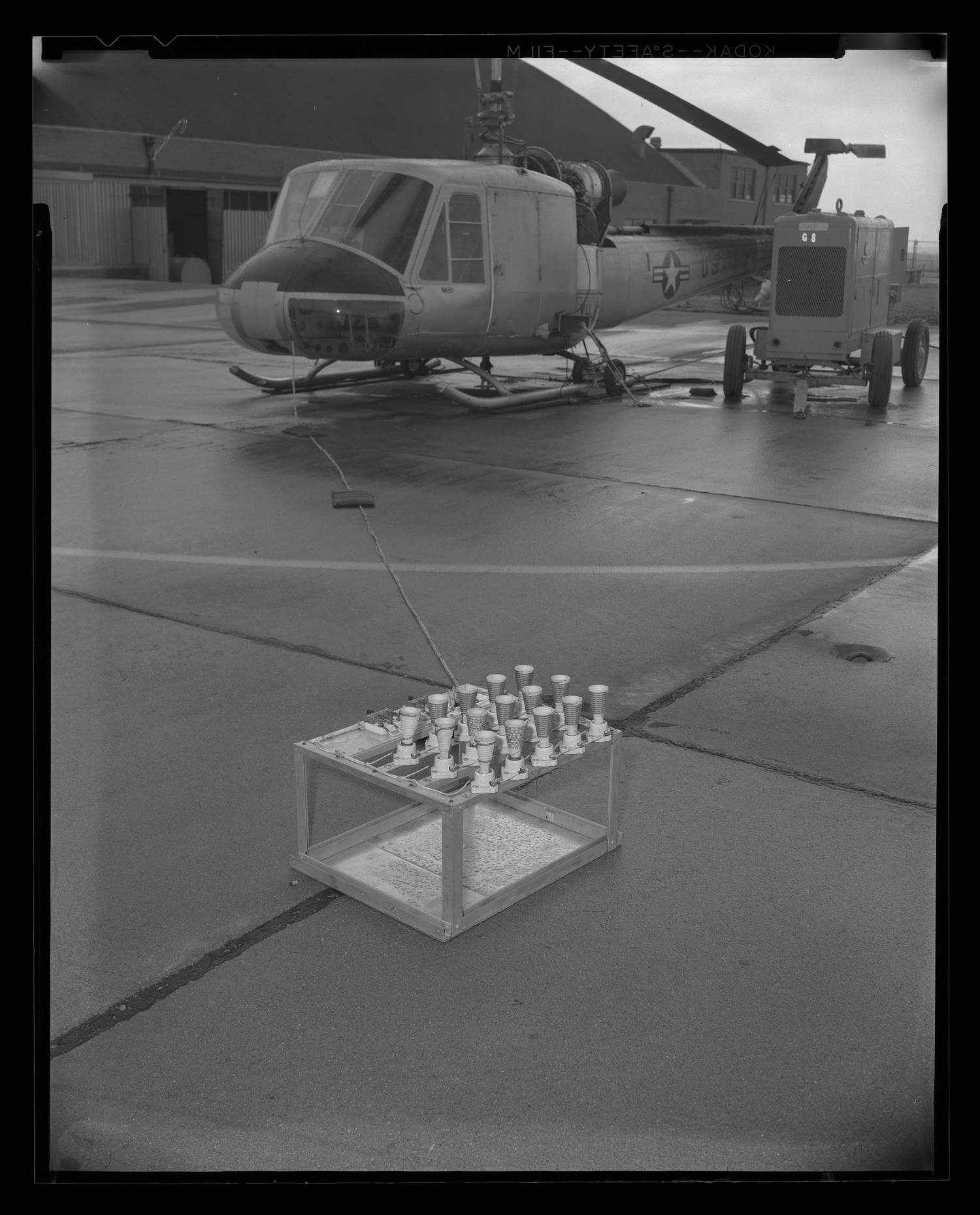 [Photograph of a UH-1B Iroquois helicopter next to a large generator]
                                                
                                                    [Sequence #]: 1 of 1
                                                