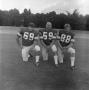 Photograph: [Three football players kneeling]