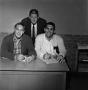 Photograph: [Three men behind a desk]