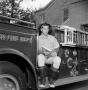 Photograph: [Bill Estes sitting on firetruck]