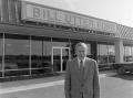 Photograph: [Man smiling in front of a Ford dealership, 4]