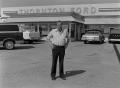 Primary view of [Howard Thornton standing in front of a Ford dealership]