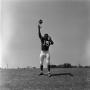 Photograph: [Football player #15, George Woodrow, stands and throws a football]