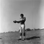 Photograph: [Football player #33, Mike Franklin, holding a football out to the si…
