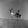 Photograph: [Football players #22 and #24 kicking a ball on an inclined grass fie…