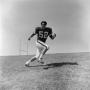 Photograph: [Football player #52 Jerry Robinson running across an inclined field]