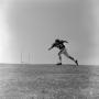 Photograph: [Football player #73, Dan Mill, running left across a grass field, 2]
